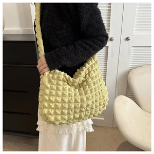 Close-up of pale green popcorn fabric tote bag with textured ruffles on a model