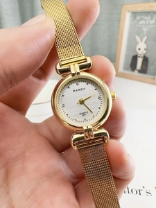 Macro shot of gold quartz watch with rhinestone markers and metallic mesh band