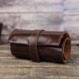 Custodia da viaggio per orologi in pelle cerata marrone scuro su sfondo di legno rustico