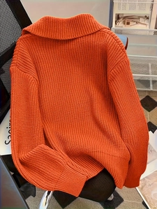 Detail of orange oversized knit cardigan showing thick fabric texture and wide collar