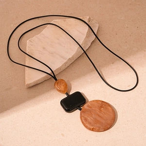 Detailed macro of the amber resin geometric pendants on a minimalist black rope necklace