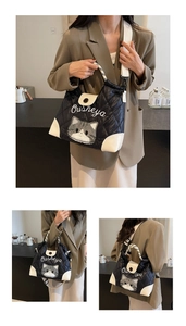 Detail of a large black puffer tote bag with cat embroidery and white handle trim