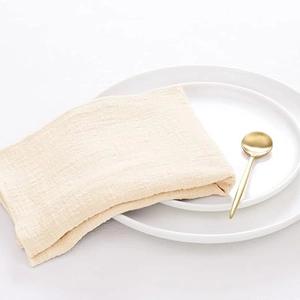 Minimalistisch beige linnen katoenen servet gevouwen op witte borden met gouden bestek