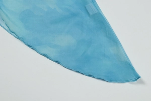 Détail du tissu en maille bleu clair avec imprimé marbré et finition ourlet ondulé