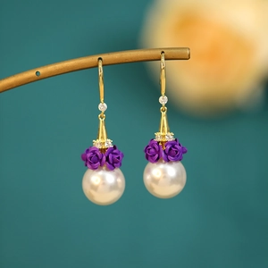 Macro shot of long drop earrings with purple roses and lustrous white pearls