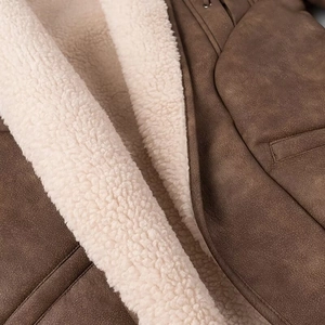 Detail of warm brown suede coat with thick cream faux shearling lining and collar