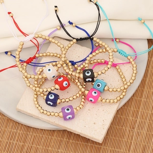 Flat lay of colorful evil eye braided bracelets with golden beads on stone and bamboo background