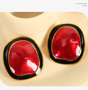Detailed macro view of irregular geometric earrings with red, black, and gold enamel finish