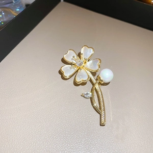 Gros plan sur la broche florale dorée ornée d'une perle et de zircons brillants