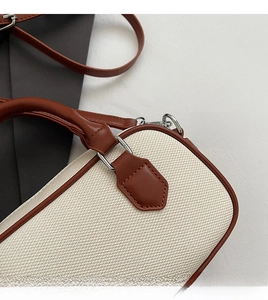 Close-up of contrast beige woven fabric and brown leather stitching on Boston bag