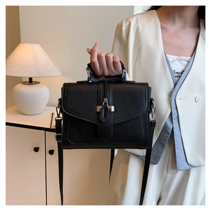 Detail of black lychee grain handbag featuring silver clasp and adjustable shoulder strap