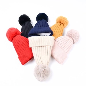 Detail of warm winter knit beanies with faux fur pom-poms and thick fleece lining texture