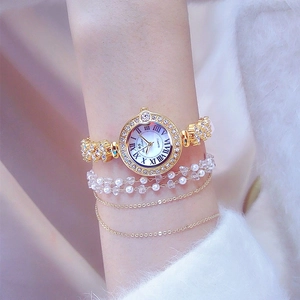 Luxury gold women's watch with rhinestone bezel and roman numerals on white fur background