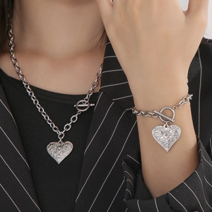 Close-up of silver OT buckle heart pendant necklace and bracelet set on a model