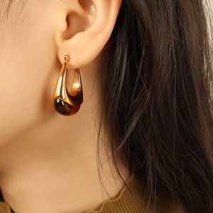 Retro gold teardrop earrings with amber resin inlay shown on model's ear