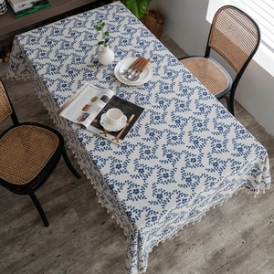 Detail of blue floral cotton linen tablecloth with elegant fringe on a wooden table