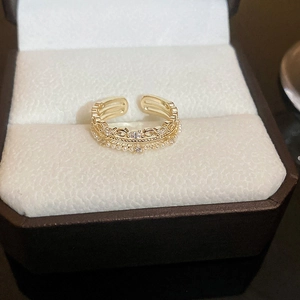 Detailed close-up of a layered 18K gold bow ring with small pearls and crystals in a box