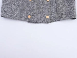 Detailed view of grey tweed fabric hem featuring textured golden buttons with relief pattern