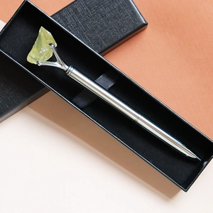 Close-up of a silver crystal ballpoint pen with yellow raw stone in a black gift box