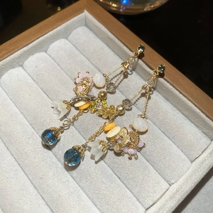 Detail of floral crystal drop earrings with golden tassels inside a velvet jewelry box