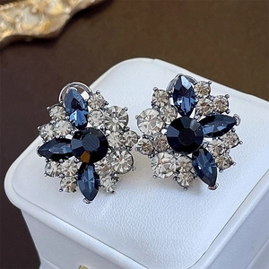 Vintage crystal flower stud earrings with blue and champagne stones on a white jewelry box