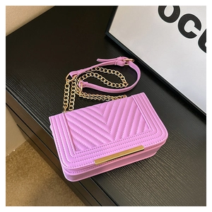 Detail of pink quilted leather bag with V-shaped stitching and gold metal bar accents