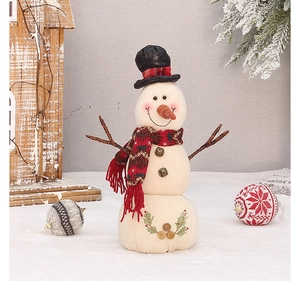 Detail of linen Christmas snowman doll with red plaid scarf and bells in snowy setting