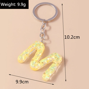 Close-up of a yellow letter M keychain with iridescent sequins and size measurements