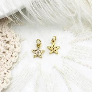 Macro shot of gold star charms with cubic zirconia on white lace and feather background
