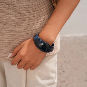 Detail of a thick navy blue resin bangle with marble texture worn by a model