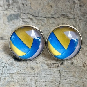 Gros plan de boucles d'oreilles en verre volleyball avec cadre argenté sur béton