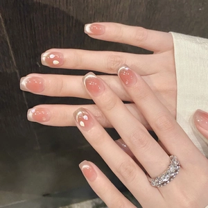 Close-up of pink gradient French manicure with floral accents and a marquise zircon ring