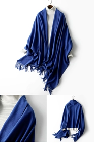 Detailed view of blue knitted scarf with tassels paired with a white turtleneck sweater