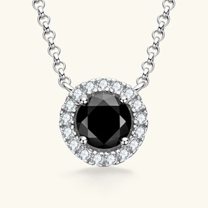 Macro shot of silver necklace pendant featuring a black round gem with diamond halo