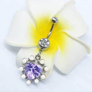 Detail of silver heart-shaped navel ring with purple crystal and pearls on a flower