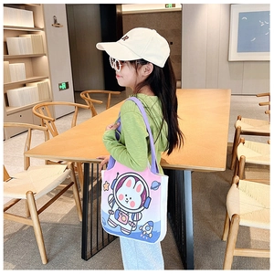Pink and blue gradient canvas shoulder bag with astronaut bunny print in a library setting