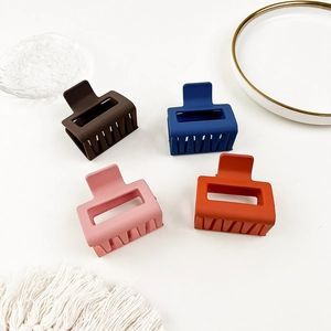 Set of four matte claw clips in brown, blue, pink, and orange on a stylish tray