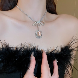 Détail d'un collier avec pendentif carré en cristal rose et nœud argenté pour femme