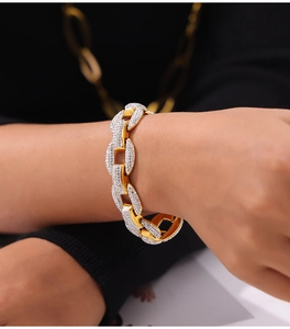 Close-up of a luxurious gold chain bracelet with white diamonds on a model's wrist