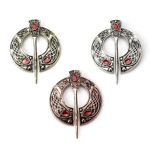 Three Celtic knot metal brooches in bronze, silver and copper with red gemstones
