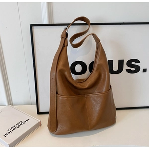 Detail view of caramel brown hobo bag featuring twin front pockets and textured soft leather