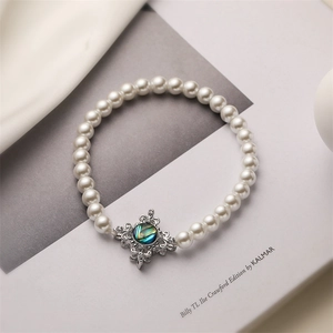 Makro-Detail eines eleganten Perlenarmbandes mit einem schillernden Abalone-Anhänger