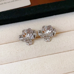 Vue macro de boucles d'oreilles fleurs argentées avec pétales pliés sur un tissu doux