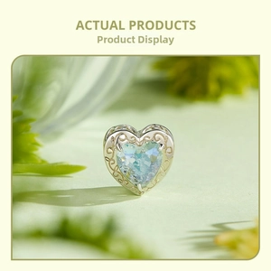 Close-up of heart-shaped S925 silver charm with hollow patterns and blue gemstone