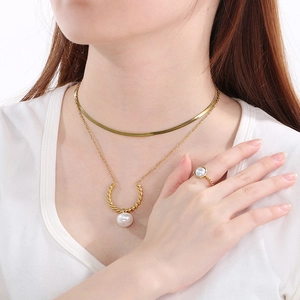 Gold layered pearl necklace and matching ring set on model with minimalist white attire