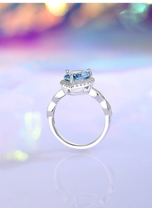 Detailed side view of silver ring with oval light blue gemstone and intricate diamond setting