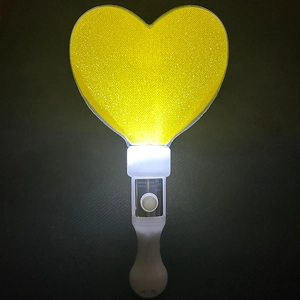 Detail of a glowing yellow heart-shaped LED glow stick for parties and concerts