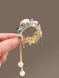 Vue détaillée d'épingle à cheveux dorée avec glands, perles bleues et finitions