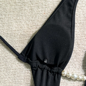 Close-up of black one-piece swimsuit featuring elegant large pearl strap details