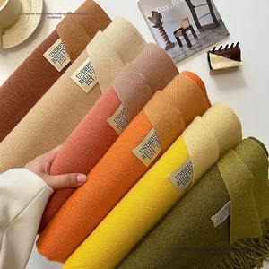 Detail view of colorful cashmere-feel scarves with woven labels and twill texture